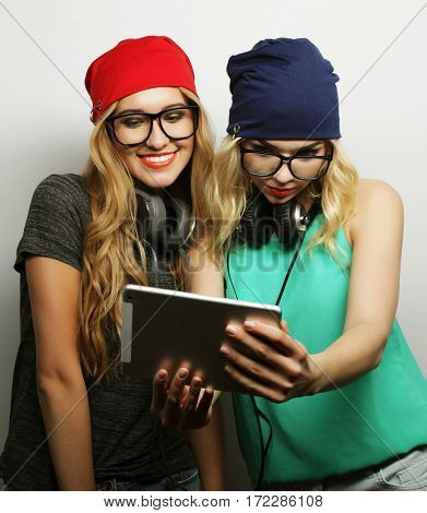 two hipster girls friends use digital tablet, studio shot over gray vackground