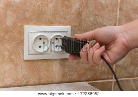 Close-up shot of male hand putting plug into socket