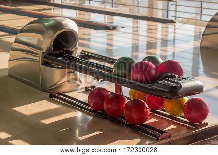 Colored bowling balls with a three finger holes on the ball return device in a modern pin bowling alley