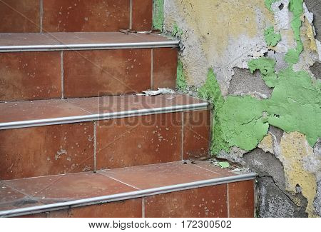 Detail of red staircase and rotting plaster on the wall