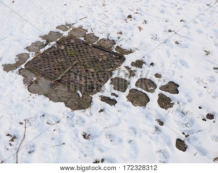 Cast iron man hole cover in winterly conditions with light snow cover Germany 2017