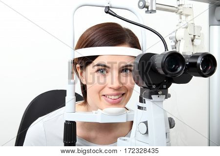 smiling woman doing eyesight measurement with optical slit lamp