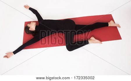 Beautiful athletic girl in a black suit doing yoga. Ardha Parivritta Nakrasana . Isolated on white background.