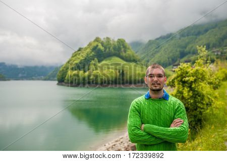 Man at beautiful emerald mountain lake Lungern in Switzerland under low clouds