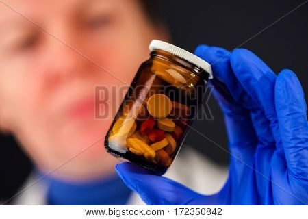 Female doctor holding unlabeled bottle of various pills and medication prescription medicine and healthcare selective focus