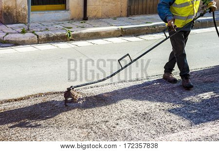 Road worker spraying bitumen emulsion with the hand spray lance before applying a new layer of asphalt