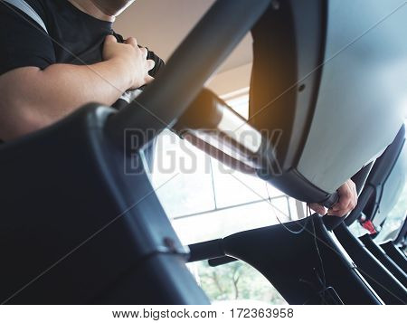 Fat man having heart attack when he working out or exercising on treadmill at a gym.