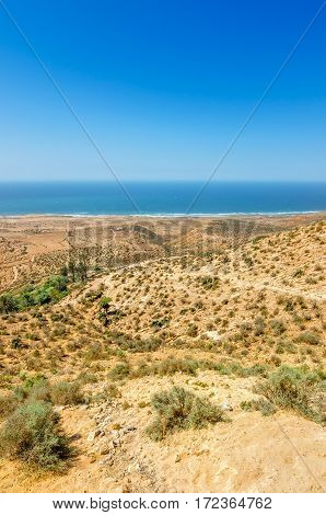 Beautiful view on oceanic beach from a high hill in Morocco in summer. Road serpentine goes towards the ocean