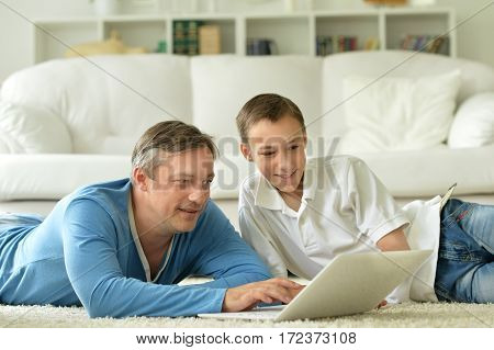 son and father using laptop at home