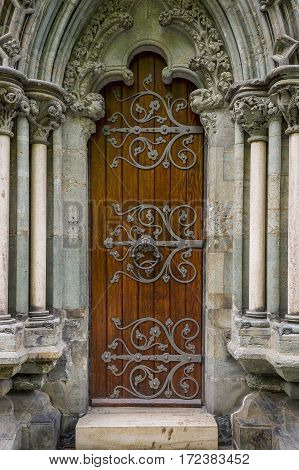 Close view at old wooden door at Nidaros cathedral stone wall, Trondheim, Norway