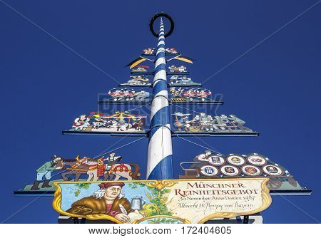 MUNICH, GERMANY - OCTOBER 31, 2015: Maypole at the Viktualienmarkt in Munich with colored figures and the brands of the local beer