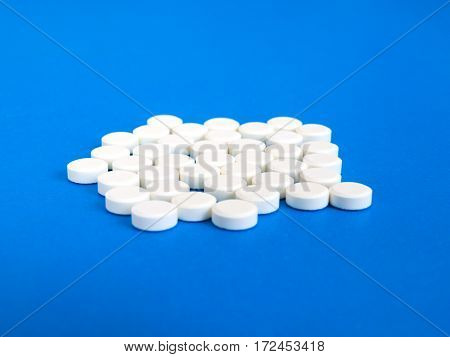 Many white pills on a blue background.