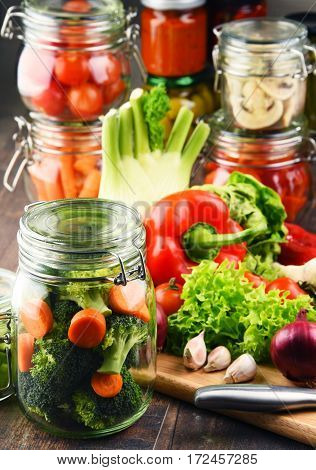 Jars With Marinated Food And Raw Vegetables On Cutting Board