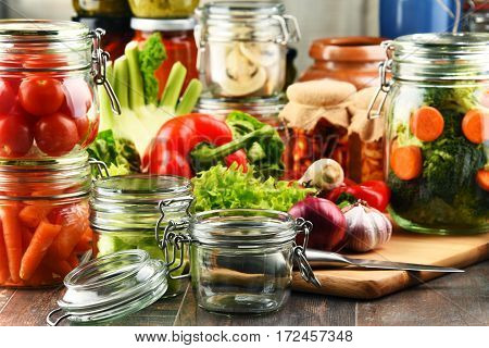 Jars With Marinated Food And Raw Vegetables On Cutting Board