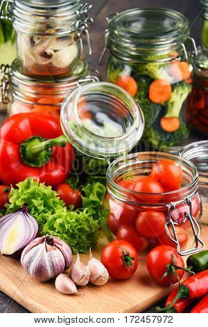 Jars With Marinated Food And Raw Vegetables On Cutting Board