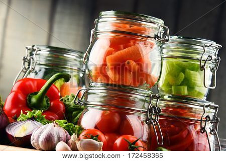 Jars With Marinated Food And Raw Vegetables On Cutting Board