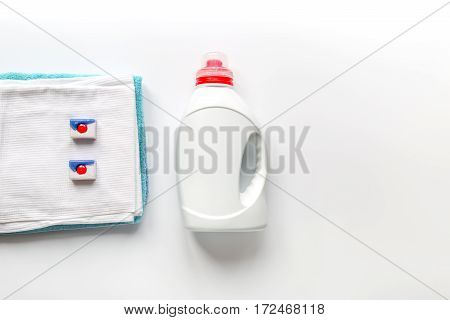 laundry set with bright towels and plastic bottels of detergent on white table background top view mock-up