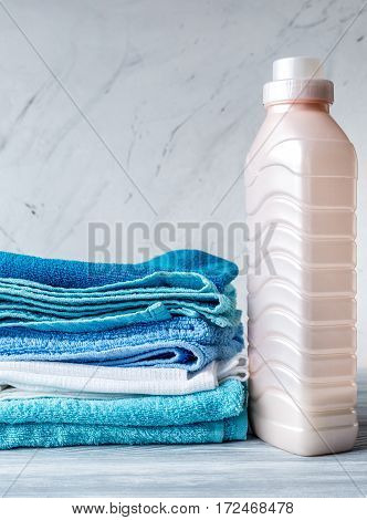 laundry set with bright towels and plastic bottels of detergent on gray table background mock up