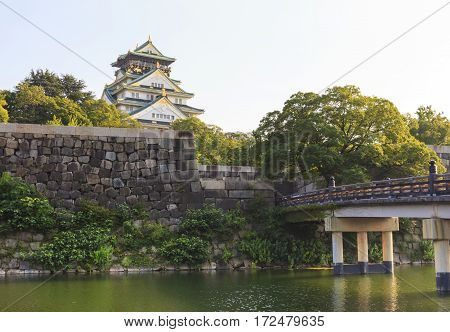 Osaka Castle with wooden Gokurakubashi Bridge in front of the castle during summer season this castle is very famous tourist attraction of Osaka Japan.