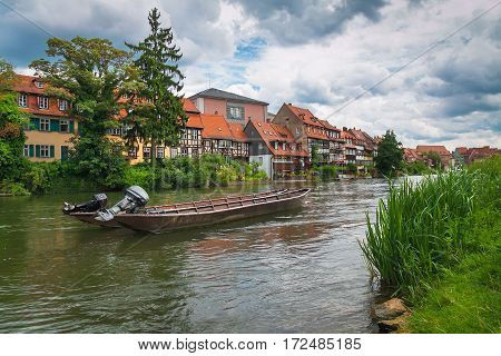 Beautiful summer landscape of the city with beautiful old houses near the river. An ancient German town. To the shore tied to the boat. In the blue sky dense clouds.