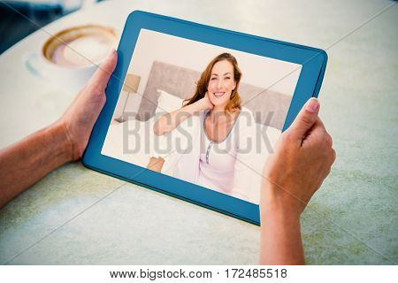 Smiling woman sitting on bed against person holding tablet computer at table in cafe