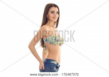 a young attractive girl in bathing bra lstands sideways and smiling isolated on white background