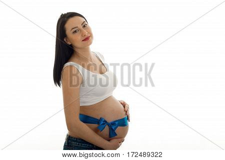 a young pregnant woman stands sideways with a Ribbon on the stomach isolated on white