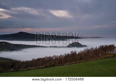 Magnificent heavy mist in landscape. Autumn creamy fog in countryside. Hill increased from fog