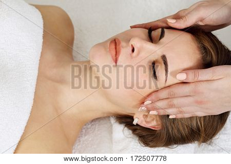 Young caucasian woman lying down receiving head massage