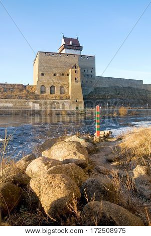 NARVA, ESTONIA - JANUARY 3, 2017: Hermann Castle Museum near The Narva (Narova) River which is the border between Estonia and Russia. Foreground is a boundary post in Russian town Ivangorod