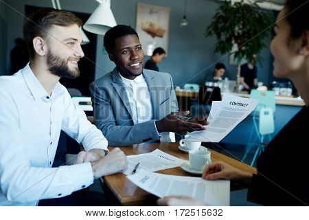 Multi-ethnic employers showing busisness contract to client