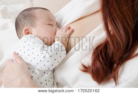 Six months old asian baby drinking breastmilk
