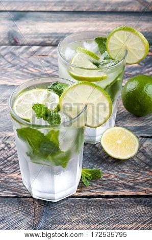 Summer cool drink mojito cocktail on rustic background. Ingredients for making mojito - lime and cane sugar. Selective focus.