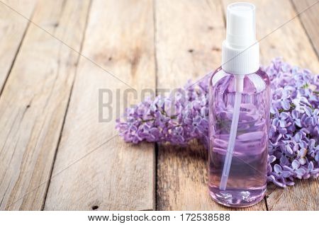 Blossoming lilac and bottle of essential oil or flower hydrolat. Spa background with copy space