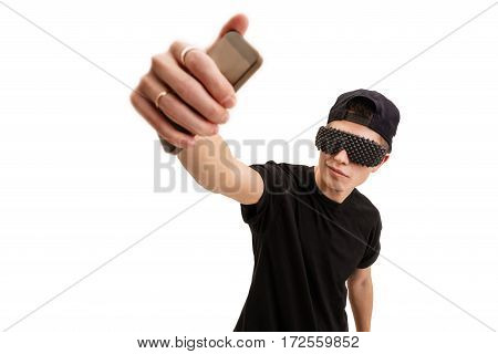 Young handsome rap dancer in black baseball cap and sunglasses making selfie in studio