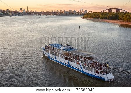 On a warm summer evening boat floats on the river, floating clouds in the sky