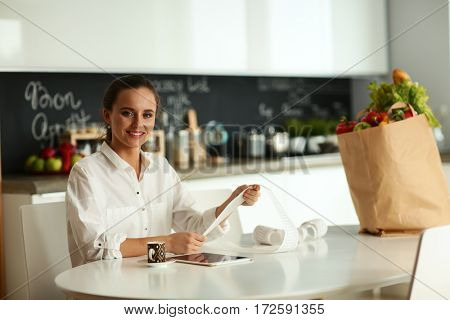 Young woman planning expenses and paying bills on her kitchen