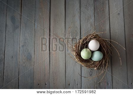 Tender colored easter eggs in a nest on a old shabby wooden table