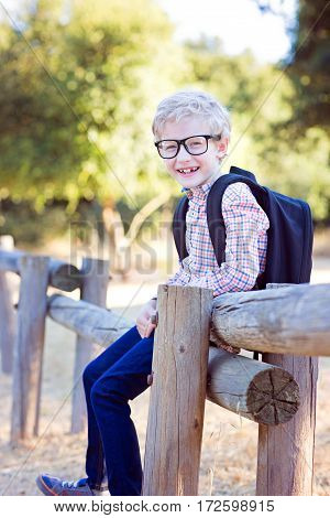 cute school boy student in glasses and with backpack enjoying time outdoor back to school concept