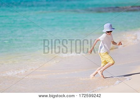 caucasian little boy running from waves at picture perfect beach enjoying summer vacation copyspace on the left