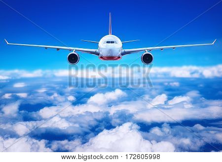 passenger airliner flying above the clouds in the blue sky