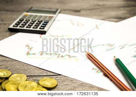 calculator, pencils and coins on graffica the Dow Jones on forex market at grey table