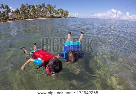 Mother and child girl snorkeling over a coral reef in a tropical resort on Vanua Levu Island Fiji. Real people copy space