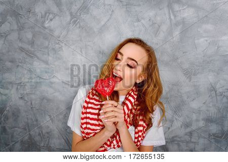 Young girl with candy near her face on the blue background