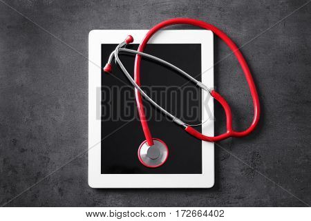 Stethoscope and tablet pc on grey table