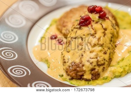 Meat patties or frikadeller in chese and mushroom sauce decorated with berries