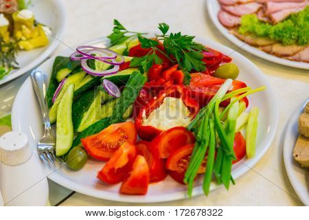 mixed vegetables on a white plate. Red peppe and tomato
