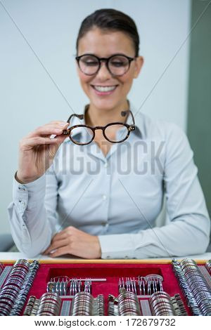 Smiling optician looking at spectacles in optical store