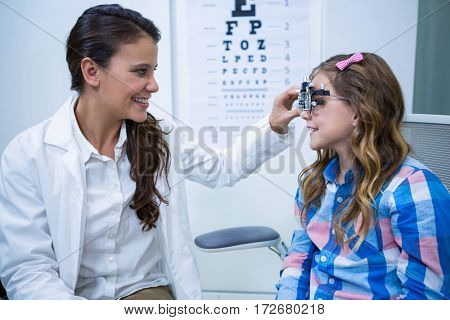 Female optometrist examining young patient with trial frame in ophthalmology clinic