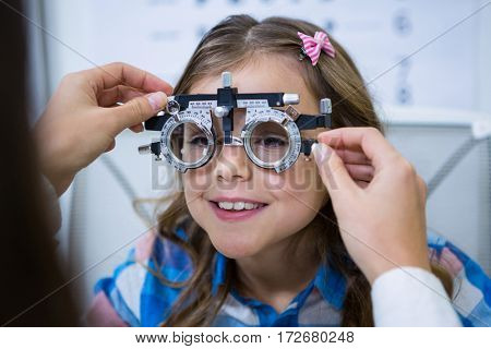 Female optometrist examining young patient with trial frame in ophthalmology clinic